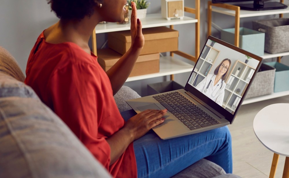 Donna in videocall con uno specialista della fertilità durante una consulenza online da casa