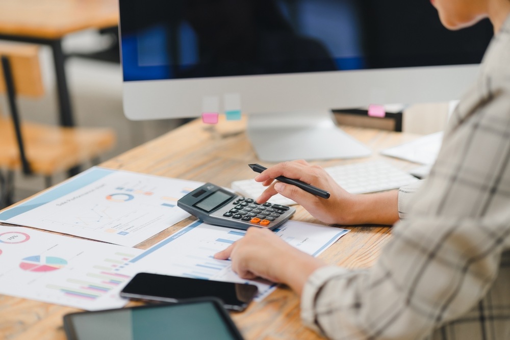Persona che valuta i costi di un percorso di fecondazione assistita con documenti e calcolatrice su scrivania