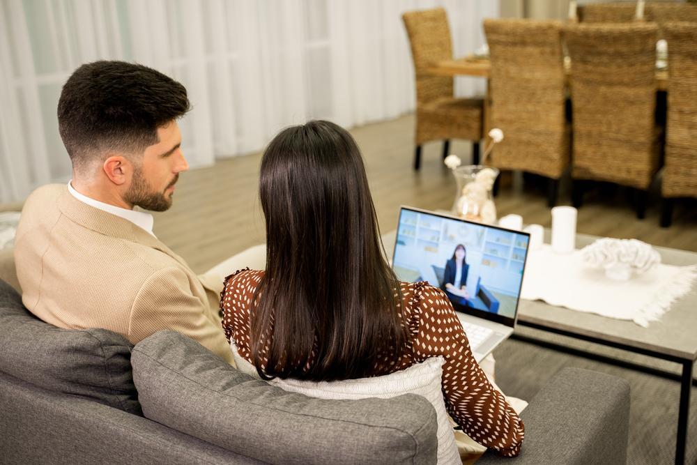 Coppia che si prepara al primo colloquio con lo specialista della fertilità davanti a uno schermo per videoconsulenza